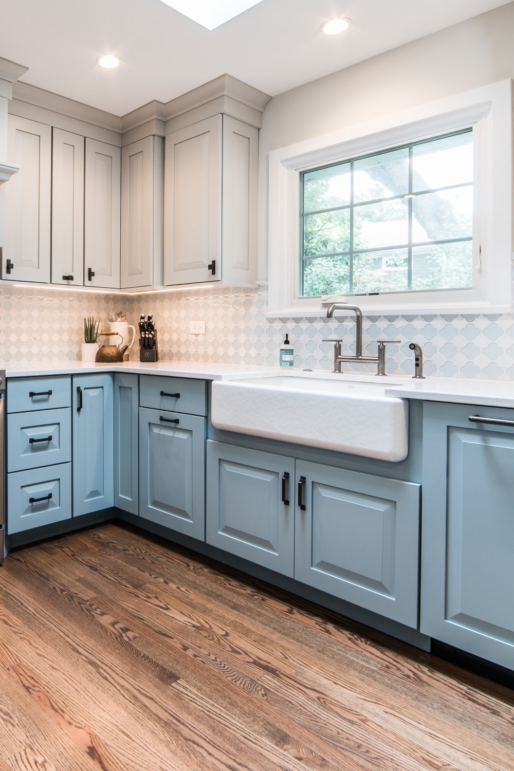 Gray Wall Blue Base Cabinets Farmhouse Sink Glass Backsplash Tiles White Countertops Dark Wood Floor