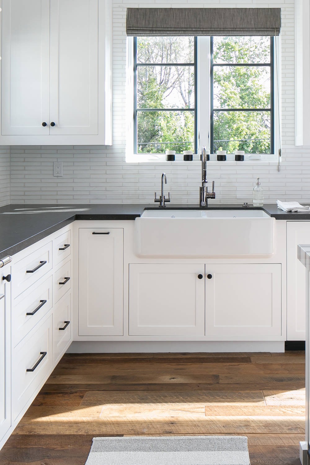 White Shaker Cabinets Tile Backsplash Honed Black Granite Countertops Medium Tone Wood Floor