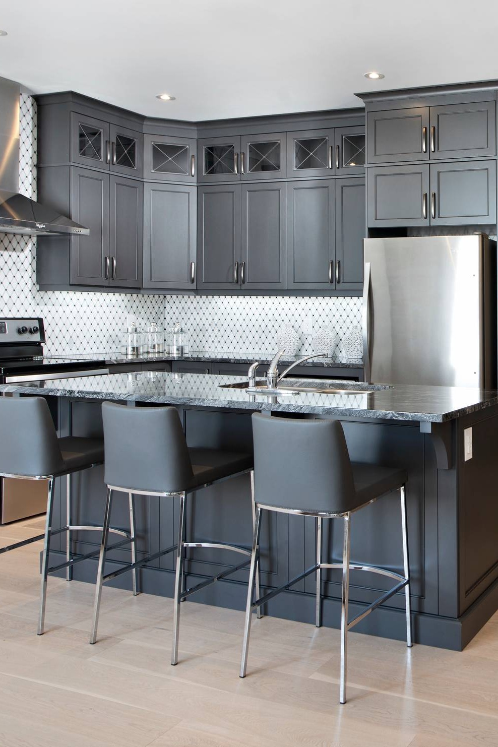 Charcoal gray Shaker Cabinets Granite Countertops Mosaic Tile Backsplash Light Wood Floor