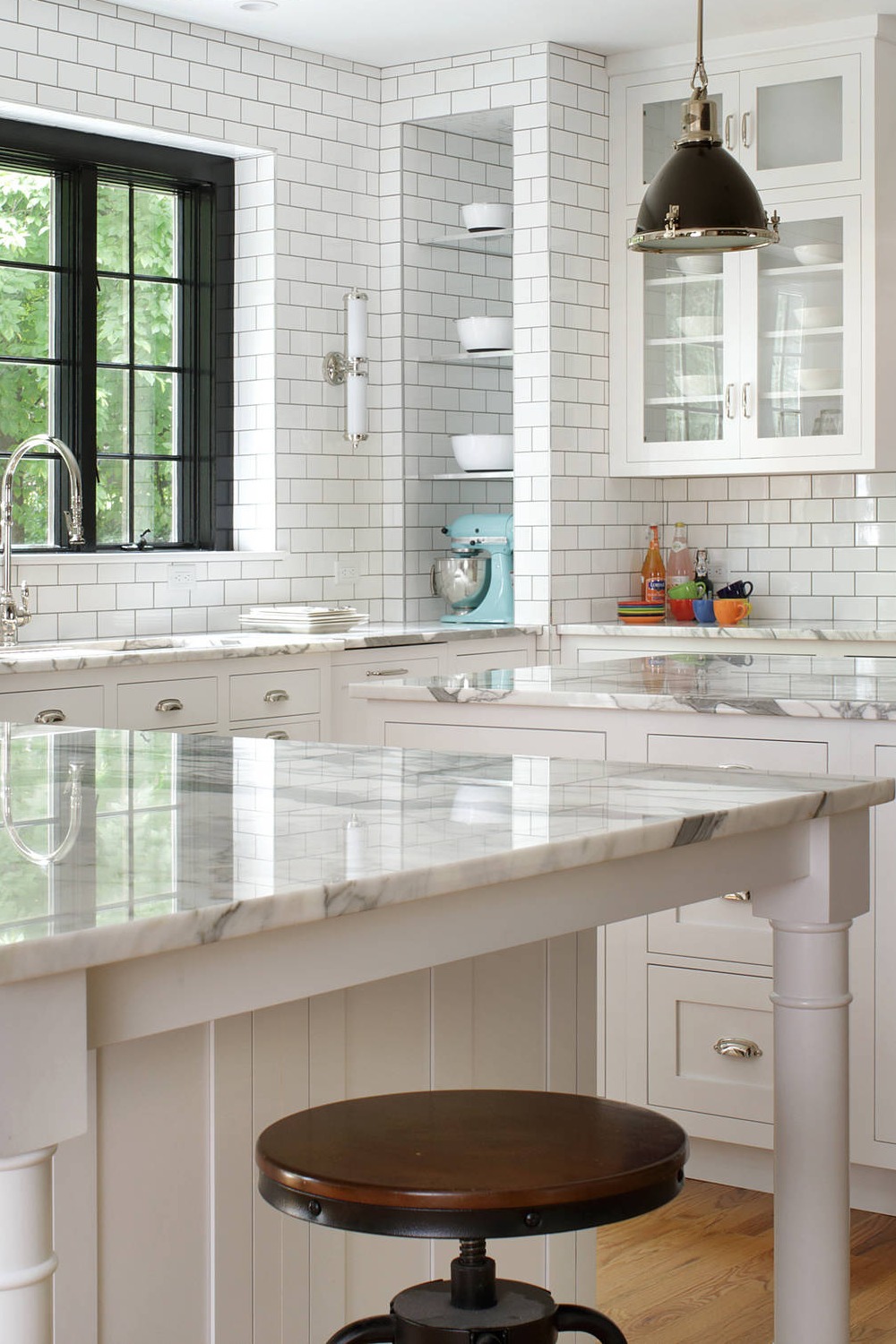 Double Island White Kitchen Cabinets Marble Counters Subway Tile Backsplash Light Wood Flooring Open Concept Pendant Lighting