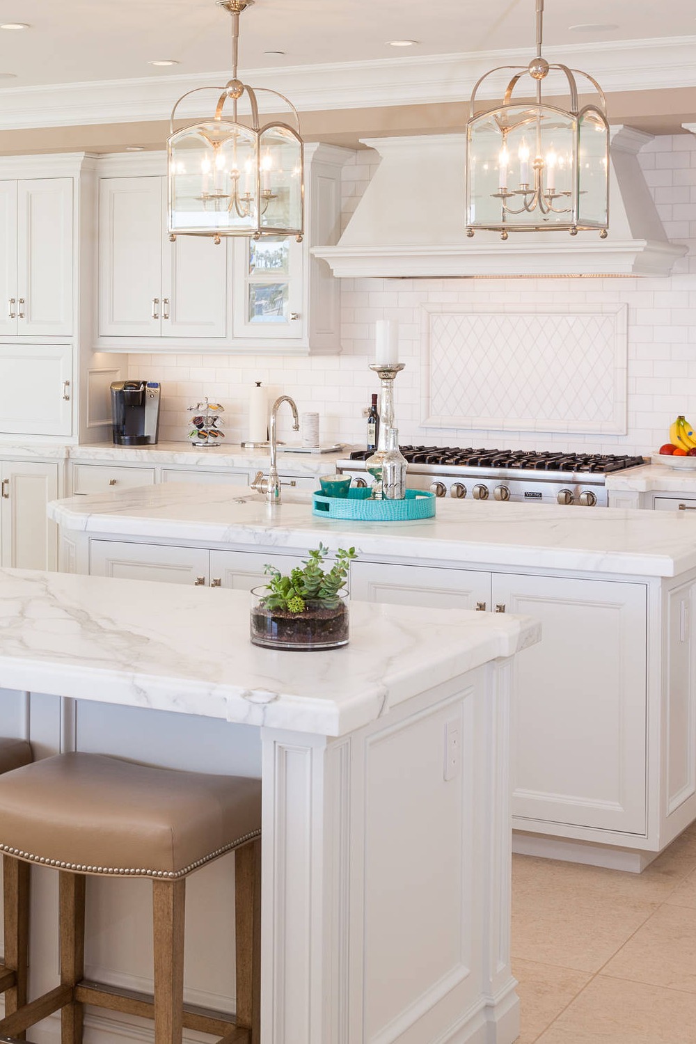 Two Islands Kitchen White Cabinets Marble Counters Subway Backsplash Cream Floor Tiles Pendant Lightings