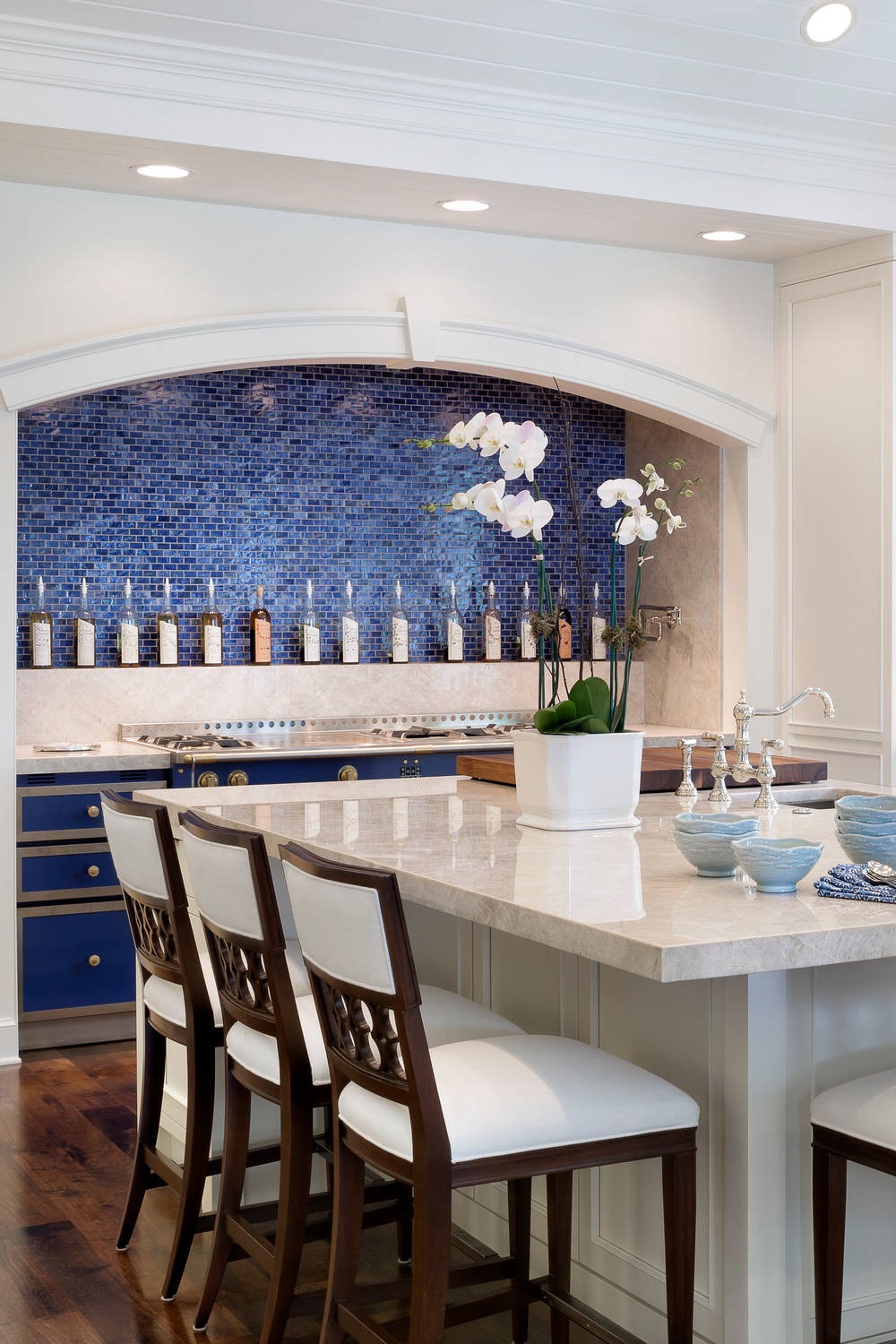 Mosaic Blue Backsplash White Cabinets White Kitchen Features Stove Room Island Dark Wood Floor Sink Quartzite Countertop